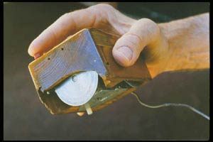 Inventor Douglas Engelbart holding the first computer mouse,[26] showing the wheels that make contact with the working surface